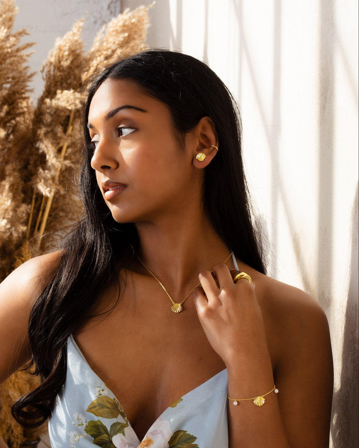 Woman wearing gold jewelry against a neutral background