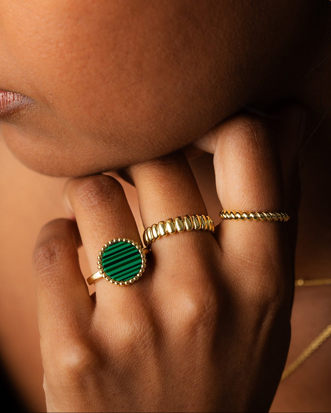 THREE GOLD VERMEIL RINGS WORN ON A WOMAN'S FINGERS