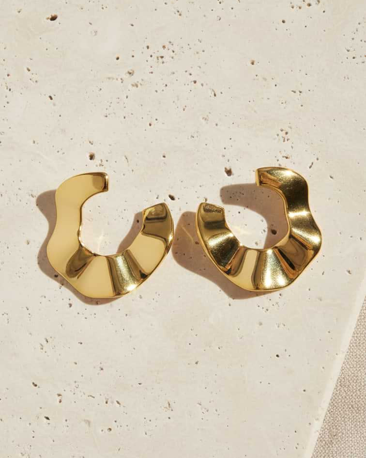 Gold hoop earrings on a textured beige surface