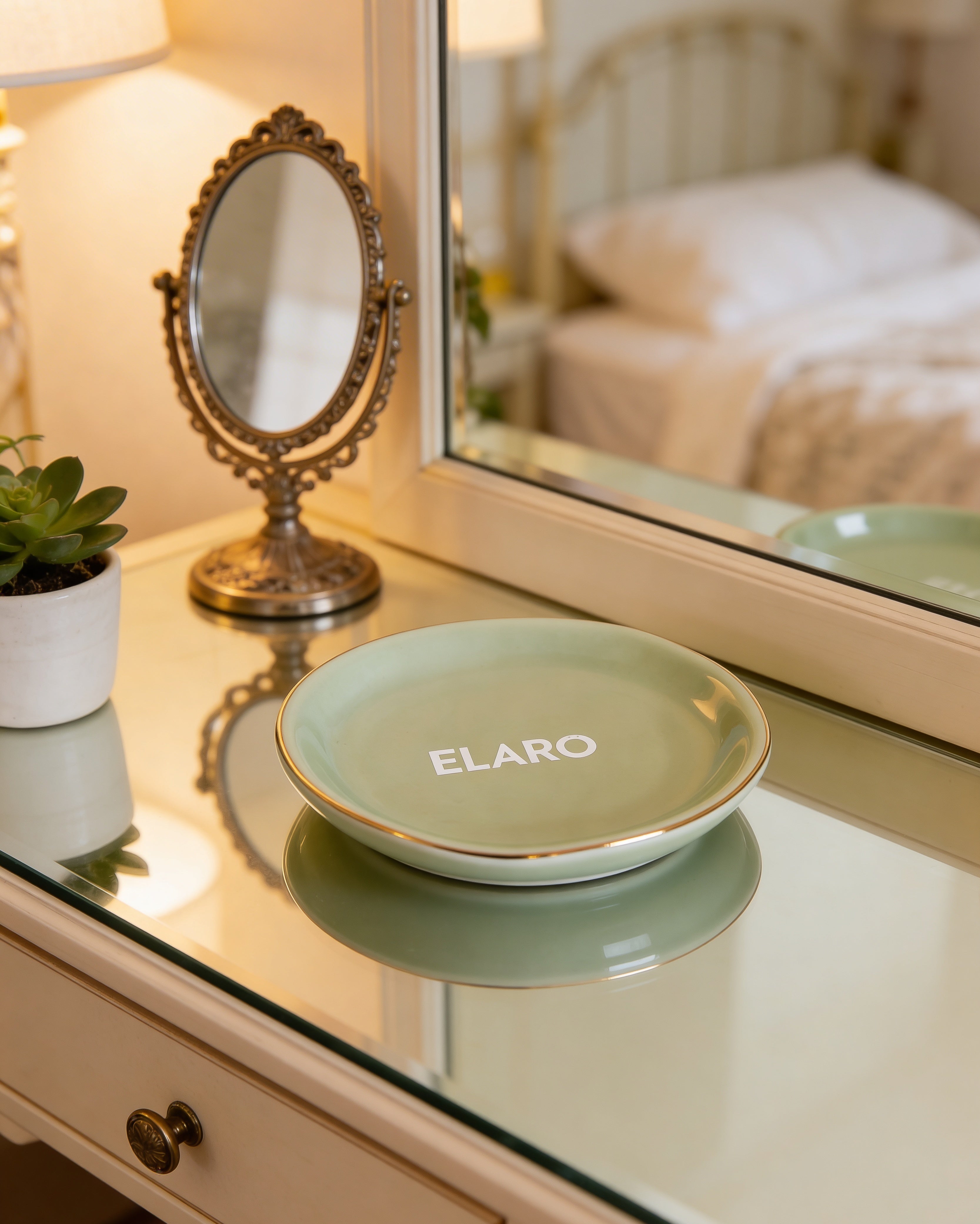 Green dish with 'ELARO' branding on a reflective surface, with a mirror and plant in the background.