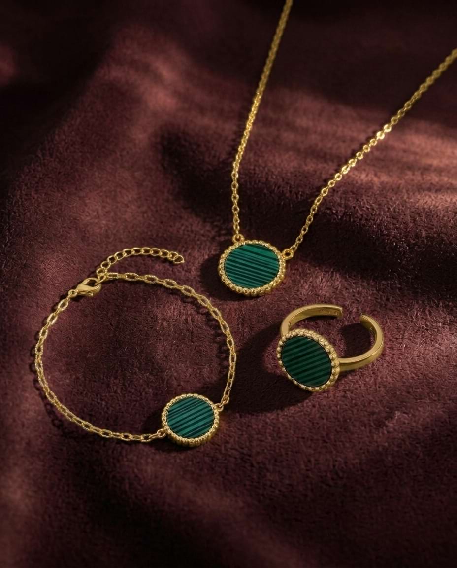 Gold vermeil jewelry set with round green malachite inlay pendants, including a necklace, bracelet, and ring, displayed on a dark burgundy velvet fabric.